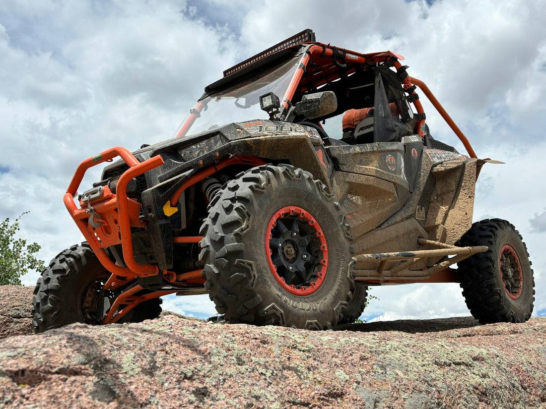 Orange and black Polaris RZR on rocky ground