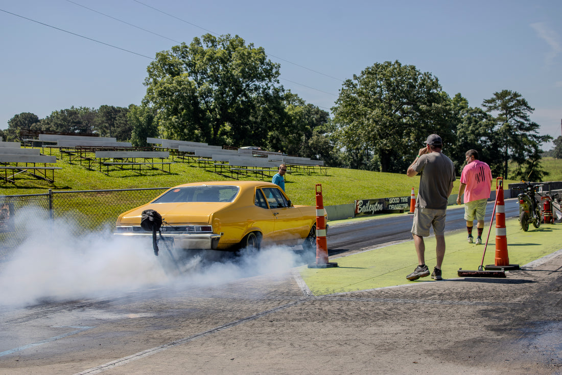 Yellow drag car performing a burnout at the dragstrip