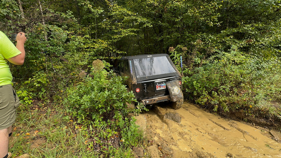 Trail rig climbing a muddy obstacle in the woods