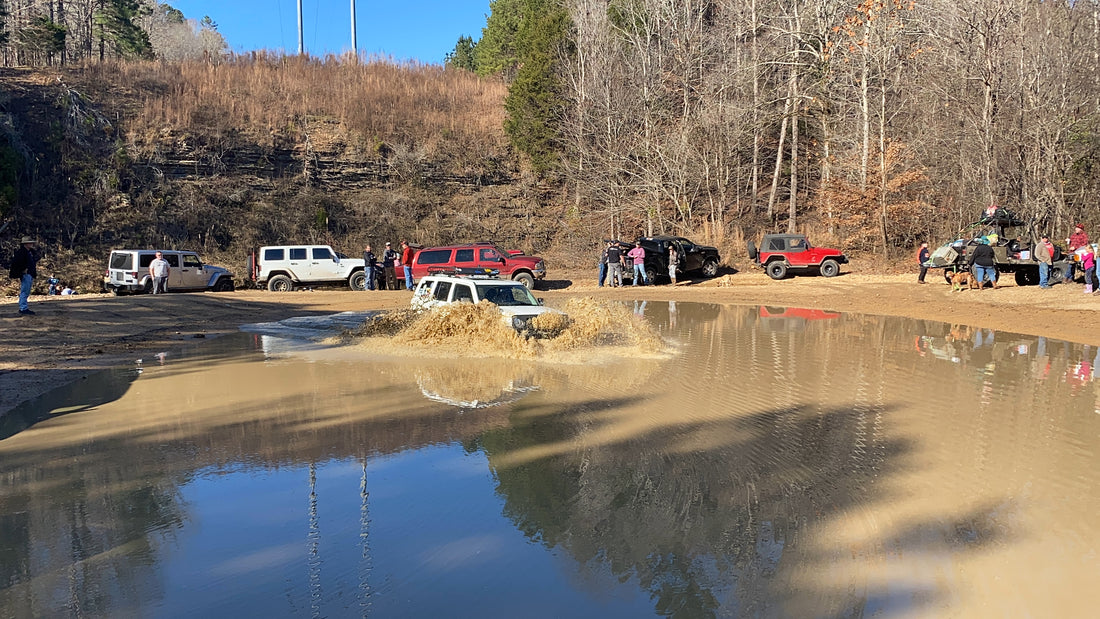 Rigs gathered around a muddy trail water crossing